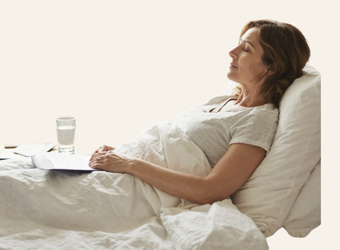 Patient resting in bed with eyes closed, water and papers within reach